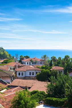 Türkiye 'nin Antalya kentindeki dikey eski Kaleici kasabası. Eski Türk evlerinin panoramik manzarası, mavi deniz ve güneşli gökyüzü.