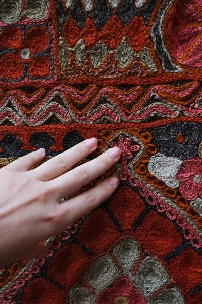 Close up young woman hand touching red Turkish carpet.Traditional icon.