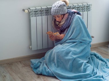 Evde oturan ve euro banknotlarını sayan bir kadın. Sıcak giyimli kadın ısıtmanın yüksek fiyatına üzülüyor. Pahalı enerji kaynakları, Avrupa 'da enerji krizi 
