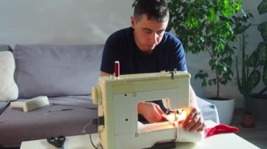 El yapımı sanayide deneyimli genç bir işçi dikiş makinesine kırmızı kumaş dikiyor, Noel Baba kırmızı şapkası üretiyor. Ev yapımı dikiş. Çalışan terzi. Noel şapkası. Kapat..