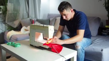El yapımı sanayide deneyimli genç bir işçi dikiş makinesine kırmızı kumaş dikiyor, Noel Baba kırmızı şapkası üretiyor. Ev yapımı dikiş. Çalışan terzi. Noel şapkası. Kapat..