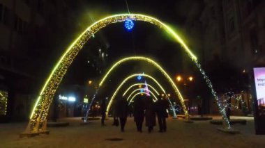 Ivano-Frankivsk, Ukrayna - Aralık 2021: Ukrayna 'nın İvano-Frankivsk kentinde kış tatilleri sırasında pek çok insanla birlikte gece parlak ışıklı yılbaşı dekoratif kemerlerinin görüntüsü. 