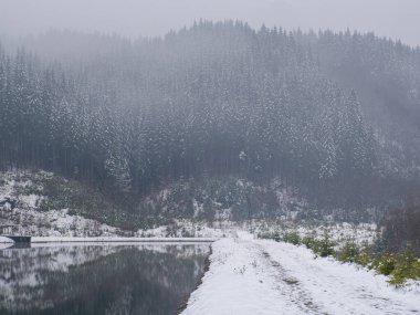 Ukrayna, Karpatlar 'da kış gölü ve orman. Bulutlu bir günde kozalaklı ormanlı manzaralar. Bukovel 'in modern popüler kayak merkezinin manzarası. Kışın Bukovel yakınlarında. 