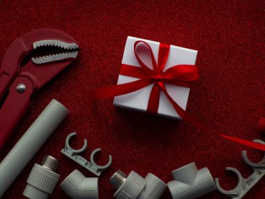 Yapı araçları ve kırmızı arkaplanda kopya alanı olan hediye. Sevgililer Günü için inşaat tebrik kartı. Evi onar. Sevgililer için hediyeler. Erkeklere hediye almak. Bir su sistemi kurulumu.