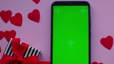 Krom ekranlı telefon ve pembe arka planda kredi kartı. Pastel pembe arka plan üzerine kırmızı kalp kağıdı, fotokopi alanı ile üst manzara. Tebrik kartı. Sevgililer Günü alışveriş konsepti. 14 Şubat. 