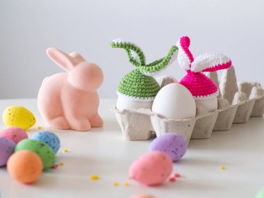 Paskalya yumurtaları için kulaklı renkli tığ işi şapkalar. Tavşan kulaklı örülmüş şapka. Paskalya tebrik kartı. Mutlu Paskalya tatili konsepti örgü örülmüş tavşan şapkalı şirin el yapımı yumurtalar ve fotokopi alanı.