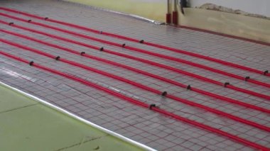 Yeni bir ev inşaatında yer altı ısıtması. Boru tesisatçısı ısıtma sistemi kuruyor. Su tabanındaki ısıtma sistemi. Tadilat sırasında apartmandaki boru tesisatı..