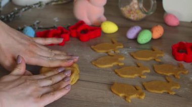 Kadınların elleri yakın plan zencefil hamuru yoğurup heykelcikleri oyuyor. Tavşan şekilleri. Paskalya şekilli kurabiye kesicilerle şekerli kurabiye hamuru kesmek. Paskalya hazırlığı. Tatil pişirme.