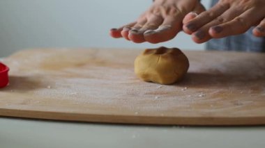 Kadın ahşap bir masada hamur yoğuruyor. Ev yapımı hamur işleri. Paskalya için pasta ya da el yapımı kurabiyeler hazırlıyorum. Noel için zencefilli ekmek pişiriyorum. Kadın fırıncının ellerine yakın bisküvi yapıyorlar..