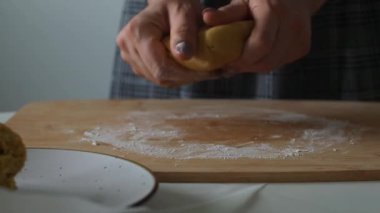 Kadın ahşap bir masada hamur yoğuruyor. Ev yapımı hamur işleri. Paskalya için pasta ya da el yapımı kurabiyeler hazırlıyorum. Noel için zencefilli ekmek pişiriyorum. Kadın fırıncının ellerine yakın bisküvi yapıyorlar..