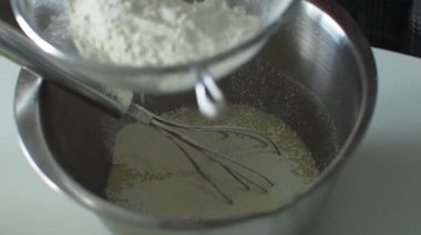 Beyaz masa arkaplanındaki metal kâseye beyaz un serpiştirmek. Elmalı pasta ve fırın için hamur hazırlığı unu. Kek, turta ve bisküvi yapmak için adım at. Pişirme işlemi adım adım