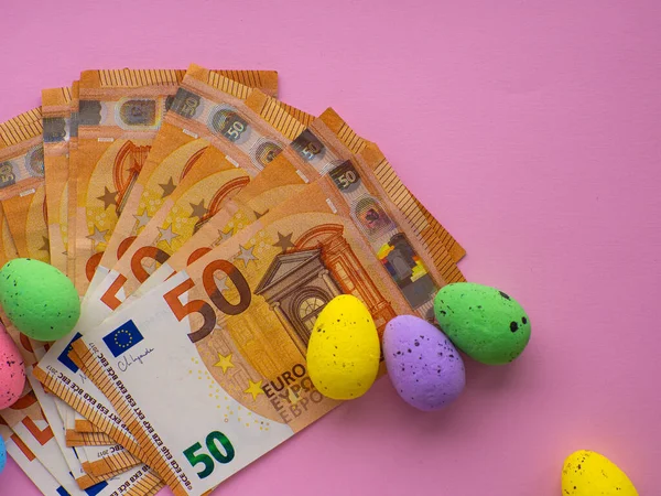 stock image Easter concept with Euro banknotes and colorful eggs on pink background. Easter and saving, spending money concept. Expensive celebration and shopping of the Easter holidays. Saving money for gifts