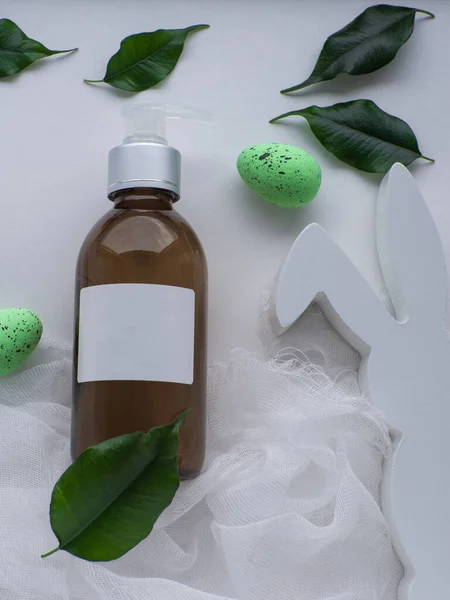 Wellness and Beauty Easter concept. Brown bottle, green eggs and white bunny. White Easter card. Cosmetics and beauty skin care in spa salon. Hygiene and spa, relaxation as a gift for holidays