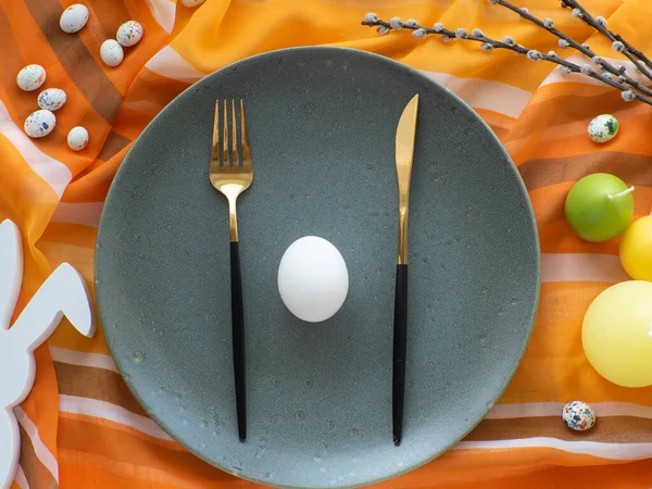 stock image Festive Easter table setting with eggs, bunny, candles and willow twig on orange background, flat lay. Elegance colorful tablescapes. Easter celebration. View from above.