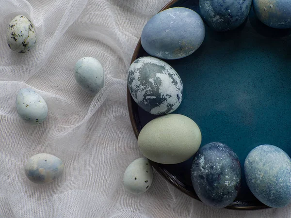 Blue painted easter eggs. Dyed Easter eggs with marble stone effect blue color on white tablecloth background. Eggs background with copy space, Ester holiday postcard concept.