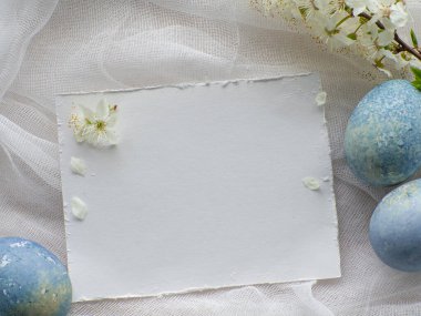 Mavi boyalı Paskalya yumurtaları. Mermer taş efektli boyalı Paskalya yumurtaları kiraz çiçekli beyaz masa örtüsü üzerine açık mavi renk. Fotokopi alanı olan yumurta arkaplanı, Ester tatil kartpostal kavramı