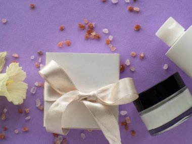 Nergis çiçeği, deniz tuzu, şişe yüz kremi ve eflatun kaplamalı hediye kutusu. Kadınlar ve Anneler Günü hediyesi. Kuaförde kozmetik ve güzellik hizmetleri. Hijyen, spa ve rahatlama bir hediye..