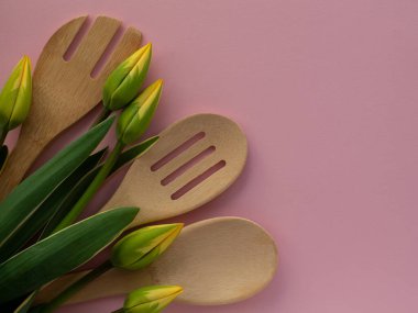 Sarı yeşil lale çiçekleri, mutfak aletleri ve pembe arka planda fotokopi alanı. Kadınlar ve Anneler Günü tebrik kartı. Doğum günü notu. Utensil buket düz yatıyordu.