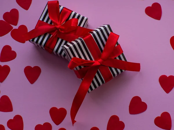 包装されたギフトボックス2つは赤いハートの紙の背景にあります グリーティングカード プレゼント バレンタインデーの休暇のコンセプト テキストのためのスペースを持つ小さな心の形の紙の多くとフラットレイアウト 2月14日 — ストック写真