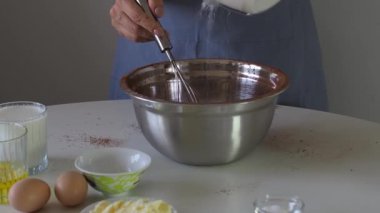 Bir kadın hamur işine şeker, kek ya da browni için metal bir fiyonk ekler. Doğum günü pastaları için hamur hazırlığı. Kek, turta ve kek yapmak için bir adım. Pişirme işlemi adım adım.