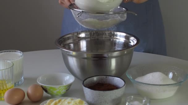 将白粉从筛子中筛入白桌上的金属碗中 用于蛋糕和烘焙的面团准备的面粉 做松饼 巧克力饼的步骤 烘焙过程 — 图库视频影像