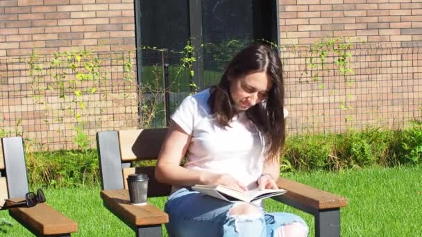 Zufriedene Brünette Frau Sitzt Auf Bank Und Liest Buch Park — Stockvideo