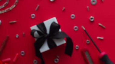 İnşaat aletleri ve kırmızı arka planda paketlenmiş hediye. Noel için inşaat tebrik kartı, Babalar, Erkekler ya da Sevgililer Günü. Evi sevgiyle onar. Sevgililer için hediyeler. Erkeklere hediye almak..