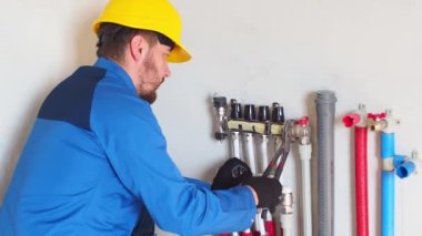 Yeraltı ısıtma tesisatı. Su tabanındaki ısıtma sistemi. Tadilat sırasında evdeki boru tesisatı. Yeraltı ısıtma manifoldu. İşçi tüpü kollektör ısıtıcısına takar