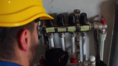 Yeraltı ısıtma tesisatı. Su tabanındaki ısıtma sistemi. Tadilat sırasında evdeki boru tesisatı. Yeraltı ısıtma manifoldu. İşçi tüpü kollektör ısıtıcısına takar