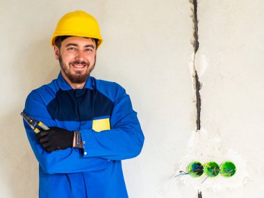 Mavi iş elbiseli işçi ya da mühendis portresi ve mesaj için yeri olan sarı kasklı. İnşaat alanında bir adam elinde bir yalıtım striptizcisi tutuyor ve kameraya bakıyor..