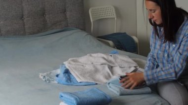 Yatak odasında temiz havlu katlayan bir kadın. Evde çamaşırları düzenlemek. Yıkandıktan sonra havlu. Minimalizm yaşam tarzı ve Japon katlama sistemi kavramı. Dolabı toparla.