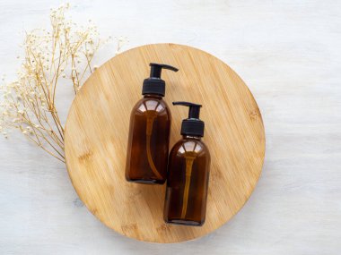 Doğal cilt bakımı SPA güzellik ürünleri tasarımı. Ahşap tabakta koyu kehribar cam şişeler. Bej arka planda mineral organik yağ kozmetiği. Model Yukarı. Yüz ve vücut tedavisi. Düz yatış, üst görünüm.