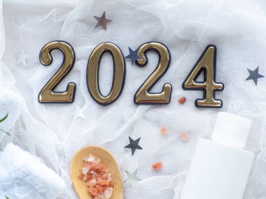 2024 yılbaşı kompozisyonu, havlular, deniz tuzu ve şişedeki vücut bakımı ürünleri. Yeni yıl sağlık kartı. Noel, vücut ve cilt bakımı. Hijyen ve spa, tatil hediyesi olarak rahatlama..