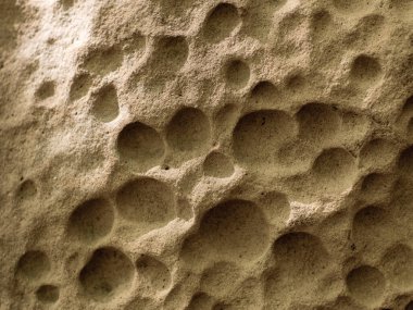 Doğal taş, bal peteği deliğine benzer. Deliklerle kaplı yıpranmış eski bir taş. Bir dağ kayasının dokusunu yakından çek. Film ve Grian simülasyonu işleniyor.