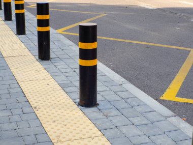Otobüs durağındaki körler için sarı dokunmatik kaldırım. Otobüs durağında yaya kaldırımını koruyan kaldırımlar var. Trafik kısıtlamasını hesaba katarsak, sürüş izni yok. Sarı, siyah sütun tamponu.