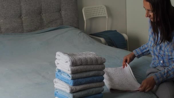 寝室にきれいなテリータオルを折っている女性 自宅で洗濯する 洗った後のタオル ミニマリズムのライフスタイルと日本の折りたたみシステムの概念 ティディ アップ ワードローブ — ストック動画