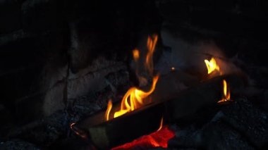 Geceleri yanan odun parçalarından çıkan güzel alevler. Sıcaklık ve dinlenme kavramı. Ateş alevleri yakar. Sıcak odun ateşi. Yakın plan. Gece şöminede el kamerasıyla ateş edilmiş..