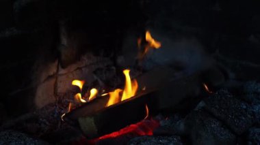 Geceleri yanan odun parçalarından çıkan güzel alevler. Sıcaklık ve dinlenme kavramı. Ateş alevleri yakar. Sıcak odun ateşi. Yakın plan. Gece şöminede el kamerasıyla ateş edilmiş..