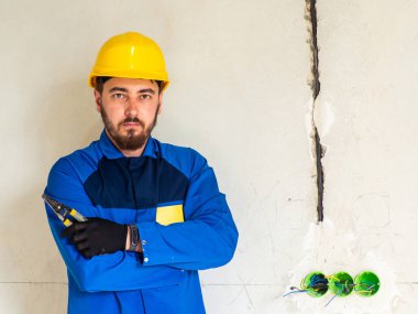 Mavi iş elbiseli işçi ya da mühendis portresi ve mesaj için yeri olan sarı kasklı. İnşaat alanında bir adam elinde bir yalıtım striptizcisi tutuyor ve kameraya bakıyor..