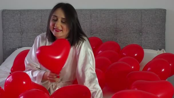 Kobieta Siedząca Pomiędzy Czerwonymi Balonami Kształcie Serca Łóżku Dziewczyna Bawiąca — Wideo stockowe