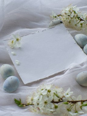 Mavi boyalı Paskalya yumurtaları. Mermer taş efektli boyalı Paskalya yumurtaları kiraz çiçekli beyaz masa örtüsü üzerine açık mavi renk. Fotokopi alanı olan yumurta arkaplanı, Ester tatil kartpostal kavramı