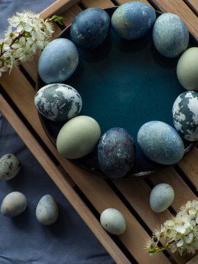 Mavi boyalı Paskalya yumurtaları. Mermer taş efektli boyalı Paskalya yumurtaları kiraz çiçekli dallarla ahşap arka planda mavi renk. Paskalya geçmişi. Boşluğu kopyala, Ester bayramı kartpostal kavramı.