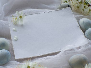 Mavi boyalı Paskalya yumurtaları. Mermer taş efektli boyalı Paskalya yumurtaları kiraz çiçekli beyaz masa örtüsü üzerine açık mavi renk. Fotokopi alanı olan yumurta arkaplanı, Ester tatil kartpostal kavramı
