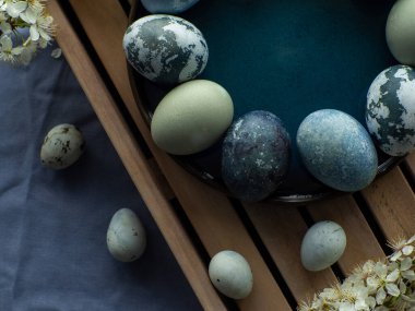 Mavi boyalı Paskalya yumurtaları. Mermer taş efektli boyalı Paskalya yumurtaları kiraz çiçekli dallarla ahşap arka planda mavi renk. Paskalya geçmişi. Boşluğu kopyala, Ester bayramı kartpostal kavramı.