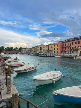 landscape of Peschiera del Garda in the province of Verona in Veneto, Italy. The main canal in a town on Garda Lake. Sunset view of Canale di Mezzo in Italian town Peschiera del Garda. clipart