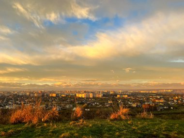 First sunrise rays of sun and shadows through fog and trees on slopes. Morning autumn Ivano Frankivsk landscape. View of the city Ivano Frankivsk from the hills near city. clipart