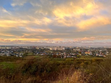 First sunrise rays of sun and shadows through fog and trees on slopes. Morning autumn Ivano Frankivsk landscape. View of the city Ivano Frankivsk from the hills near city. clipart