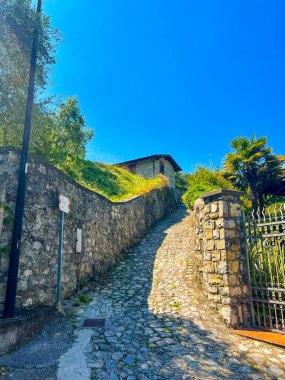 Carzano, İtalya 'nın büyüleyici manzarasını keşfedin, antik taş bir çitin yanında güzel bir taş yol esiyor, sizi zengin tarihi ve manzaralı güzelliği deneyimlemeye davet ediyor..
