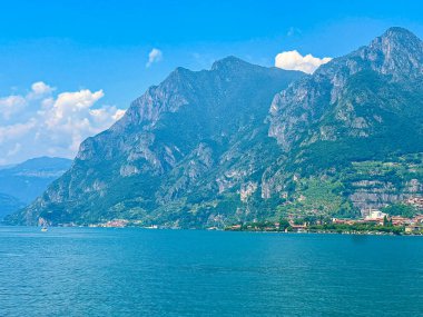 İtalya 'daki mavi gökyüzünü yansıtan sakin bir Iseo gölünün olduğu çarpıcı bir manzara. Yeşillik tarafından çerçevelenmiş görkemli dağlar uzaklardan yükselir. Huzurlu ve görkemli bir manzara yaratır..