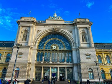 Budapeşte, Macaristan 11 Aralık 2023: Budapeşte 'deki Fransız tarzı bir tren istasyonunun ihtişamı, etkileyici mimarisini mavi gökyüzünün arka planına karşı sergiliyor. Büyük giriş odak noktasıdır..